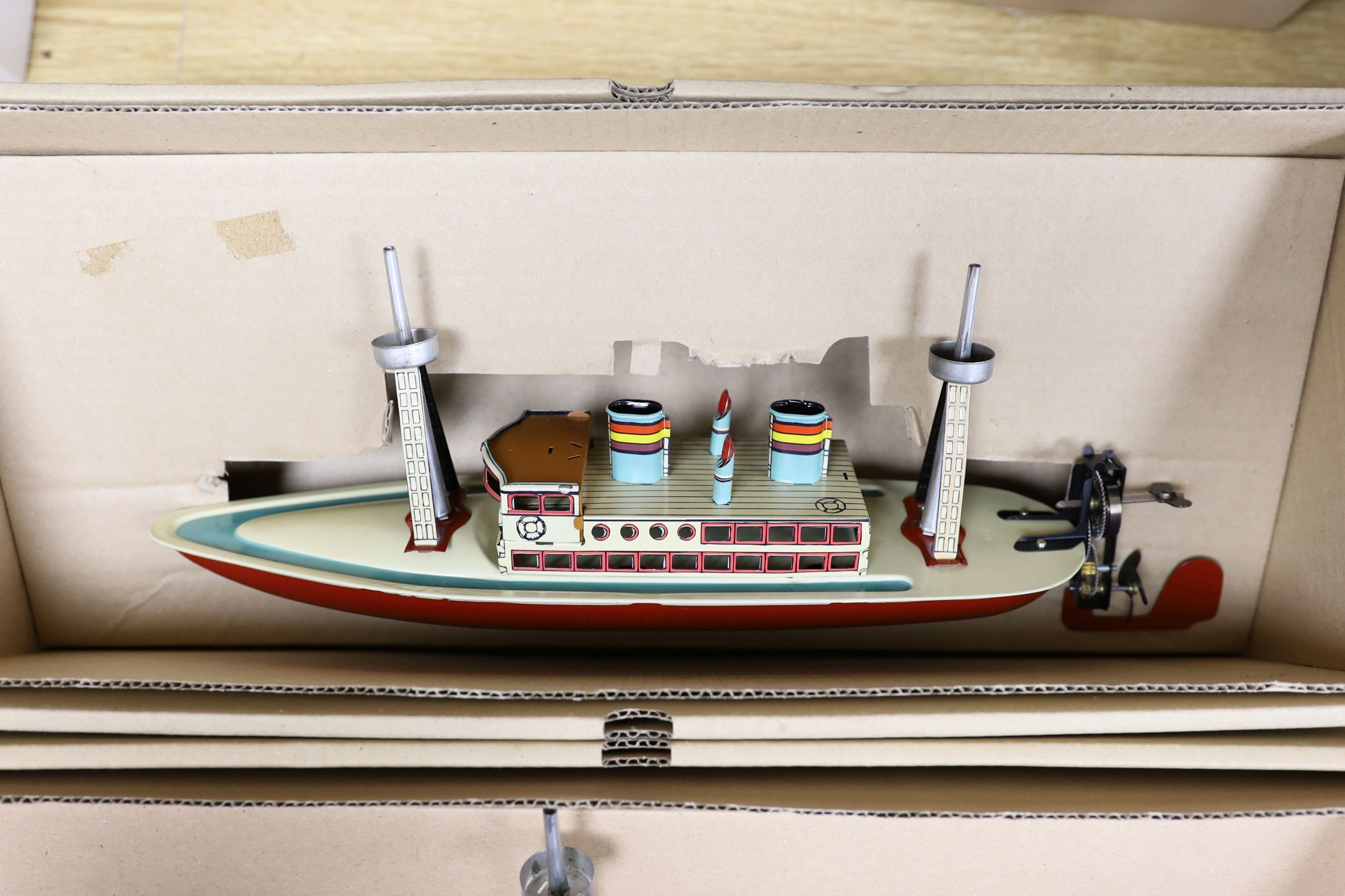 Three IBA tinplate boxed toys, two boats and a train, largest boat 42 cms wide.